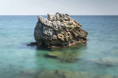 Rock formation in sea against sky