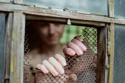 Portrait of young woman lying on metal fence