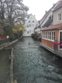 Buildings by river against sky in city