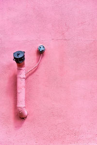 Close-up of pipes on pink painted wall
