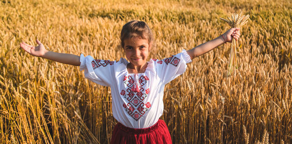Portrait of smiling girl with arms outstretched standing in farm