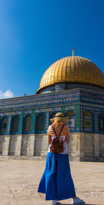 Rear view of woman looking at mosque against clear blue sky