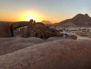 Rocks on land against sky during sunset