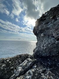 Rock formation on beach against sky