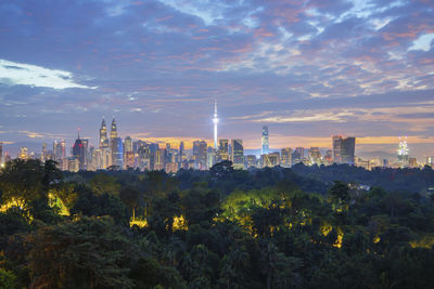 View of trees and buildings against cloudy sky