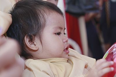 Close-up of cute baby girl with runny nose and tears looking away