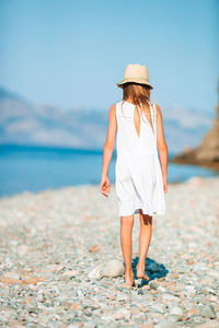 Rear view of woman standing at beach against sky