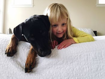 Girl and dog lying on bed at home