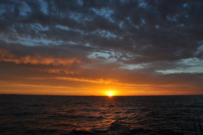 Scenic view of seascape against cloudy sky during sunset