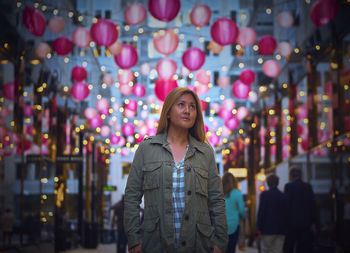 Young woman standing against illuminated lights at night