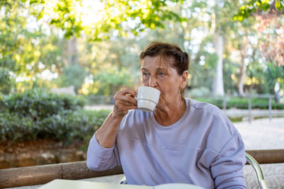 Young woman drinking water while sitting outdoors