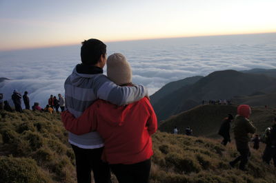 Rear view of man and woman against cloudy sky