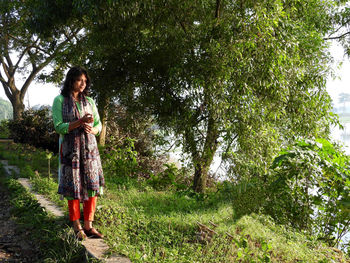 Full length of woman standing by tree