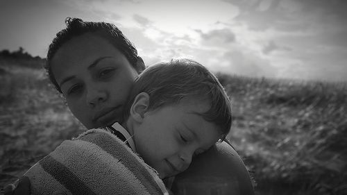 Portrait of mother embracing son on field