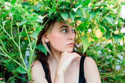 Portrait of young woman standing against plants