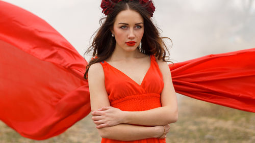 Woman in red dress looking away against sky