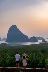 Rear view of people standing on mountain during sunset