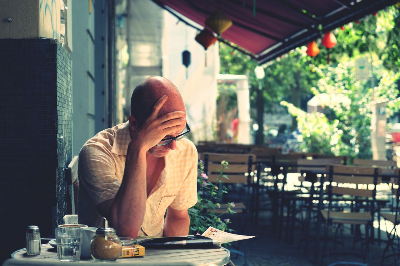 sitting, indoors, lifestyles, rear view, casual clothing, leisure activity, chair, standing, focus on foreground, full length, person, men, window, table, side view, three quarter length, relaxation, waist up