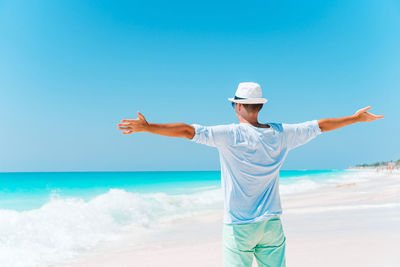 Rear view of man standing at beach against sky