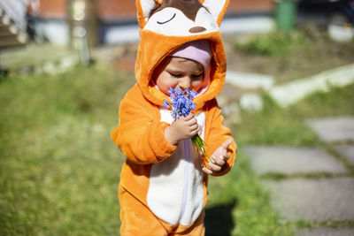 Charming toddler with spring flowers outdoors in sunlight