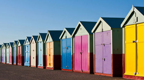 Multi colored beach huts against clear blue sky