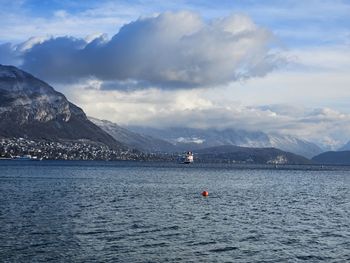 Scenic view of lake and mountains against sky with beautiful white clouds