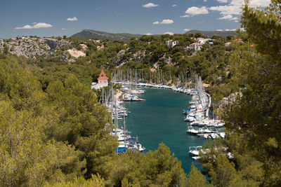 High angle view of sailboats by trees against sky