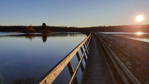 Pier over lake against sky during sunset