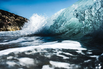 Water splashing in sea against blue sky