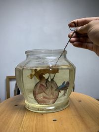 Midsection of person holding glass container on table