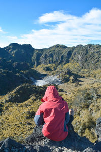 Rear view of woman standing on mountain against sky