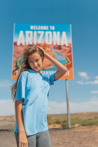 Portrait of young woman standing against sky