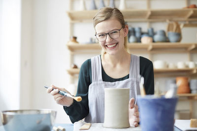 Portrait of smiling young woman learning pottery in art studio