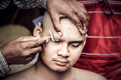 Close-up of hairdresser cutting eyebrows of man