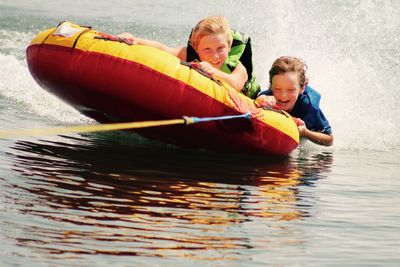 Two boys having fun on raft pulled by boat