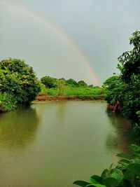 Scenic view of rainbow over lake against sky