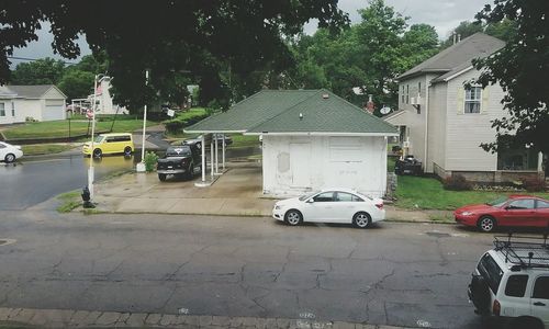 Cars on road by house against sky