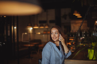 Middle aged woman talking on a cell phone in a cafe