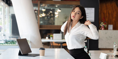 Young woman using phone while standing on table