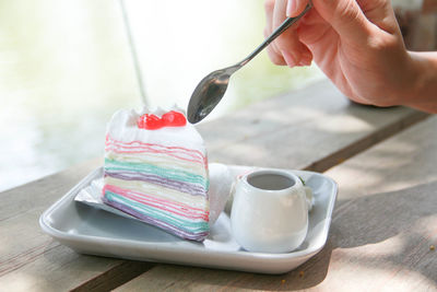 Close-up of hand holding coffee cup on table