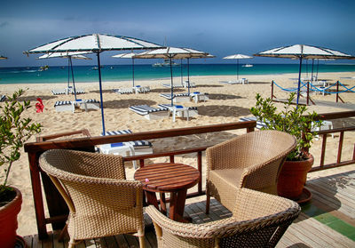 Chairs and tables on beach against sky