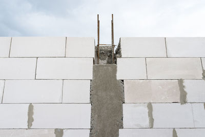 The walls of a house built of white brick with reinforced concrete pillars at the end of which