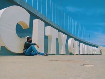 Man sitting on seat against sky