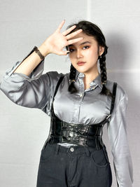 Portrait of young asian woman standing against wall