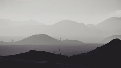 Scenic view of silhouette mountains against sky during fog