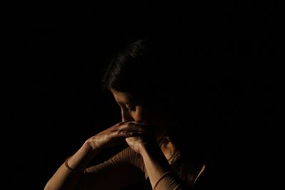 Close-up of woman looking down against black background