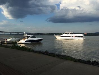 Boats in sea against cloudy sky