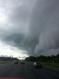 Cars on road against cloudy sky