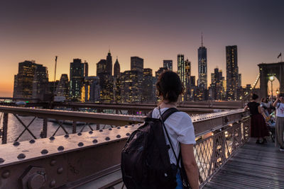 Rear view of bridge and buildings against sky during sunset