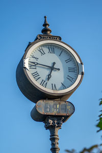 Low angle view of clock against clear blue sky